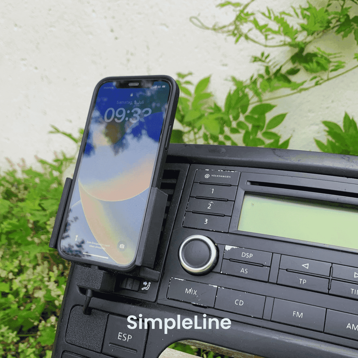 VW T5 Armaturenbrett mit montierter beev.holder Handyhalterung, iPhone eingesetzt, umgeben von grüner Natur im Hintergrund.