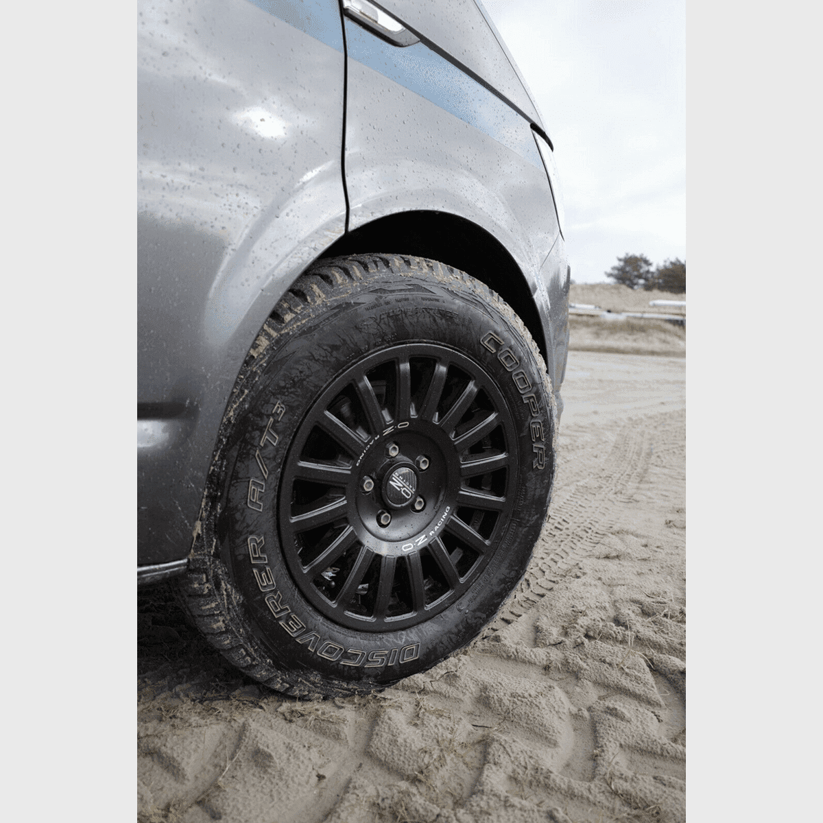 OZ Rally Raid Offroad Felge an einem VW T5-T6.1 auf sandigem Gelände montiert, robustes Design für Offroad-Abenteuer.