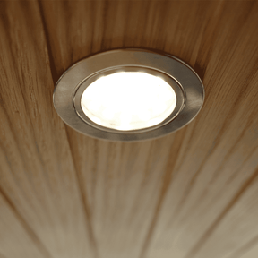 Touch LED Spot 12V 1,55W in warmweiß, eingebettet in eine Holzdecke mit gebürsteter Nickel-Optik, leuchtet sanft.