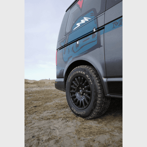 OZ Rally Raid Offroad-Felge am VW T5-T6.1 auf sandigem Gelände, seitliche Fahrzeugnahaufnahme mit Fokus auf den Reifen.
