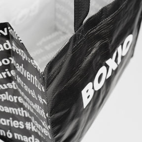 Schwarze BOXIO BAG Tragetasche mit gewebtem Henkel und weißem Logo sowie Schriftzug aus Recyclingmaterial, nah aufgenommen