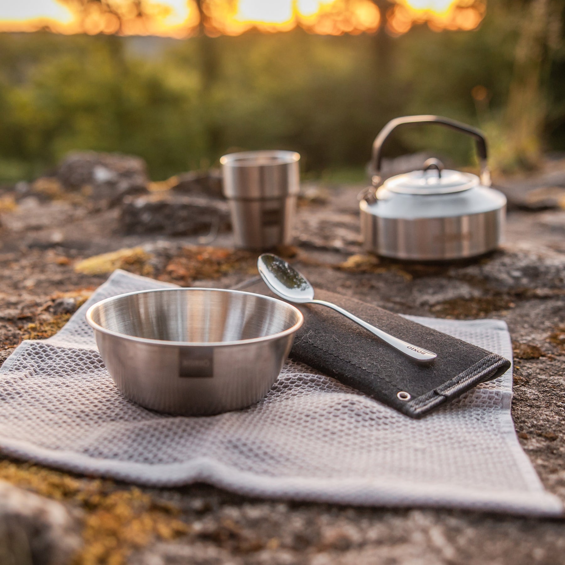 BOXIO COOK UP Camping-Kochset aus Edelstahl mit Schüssel, Becher, Löffel und Topf auf Tuch im Freien