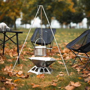 BOXIO TRIPOD über Feuerschale im Herbstrasen mit Hängekessel und umlaufender Kette, daneben Campingstühle und Tisch
