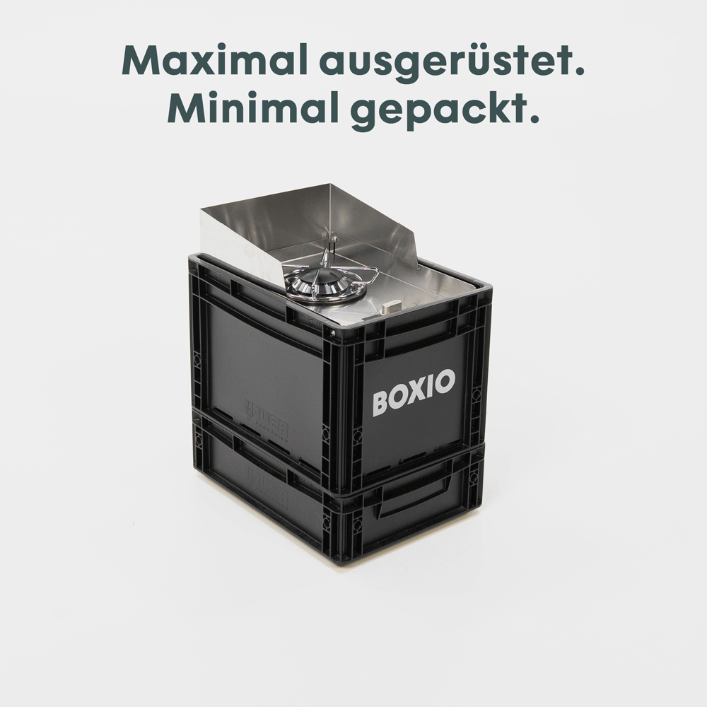 BOXIO COOK MAX+ Camping-Kochset aus schwarzer Kiste mit Edelstahlkocher und Windschutz; darüber Schriftzug „Maximal ausgerüstet. Minimal gepackt.“